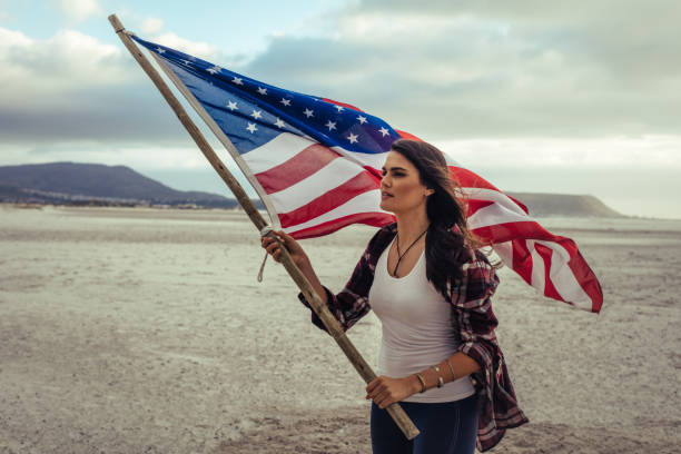 istock Attractive woman with American Flag on beach 1166228225