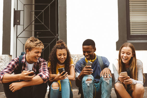 istock Friends sitting outdoors holding cell phones 1166230234