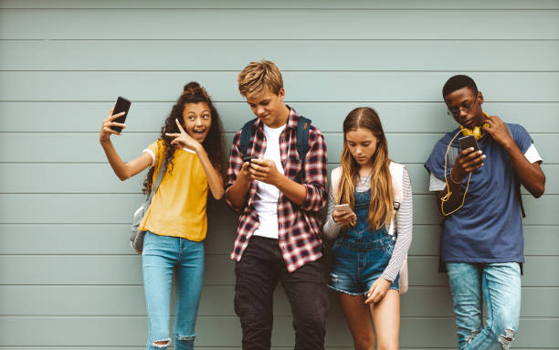 amis d'adolescent regardant leurs téléphones portables - mobile phone group of people photographing teenager photos et images de collection