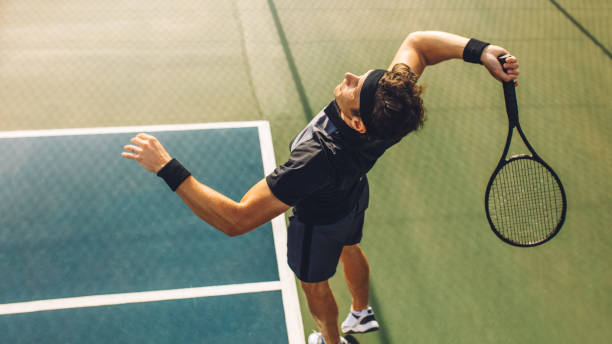 Tennis player serving in the match Top view of young tennis player jumping to hit the ball from the baseline of a hard court. Professional tennis player about to hit the ball for the serve. taking a shot sport photos stock pictures, royalty-free photos & images