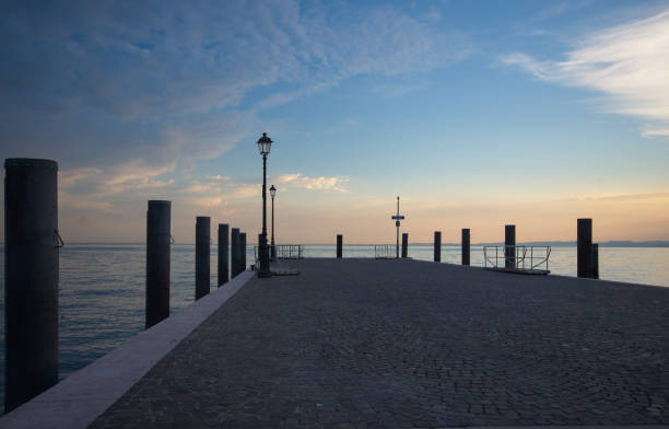 a dock at sunset on still water with a light post in italy - black blue escape multi colored imagens e fotografias de stock