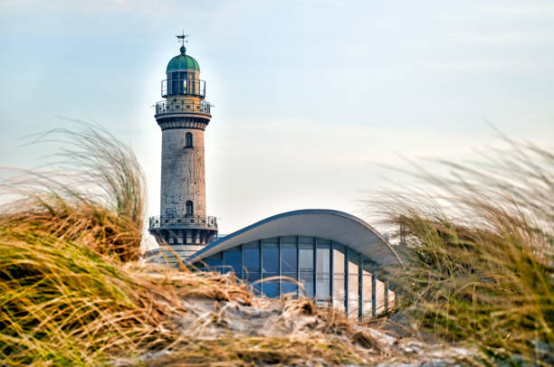 latarnia morska w warnemünde (niemcy) za wydmami pokrytymi trawą marram - lighthouse sea beach germany zdjęcia i obrazy z banku zdjęć
