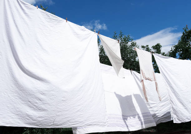 istock Snow-white clean sheets hang on a rope and dry outdoors 1166244119
