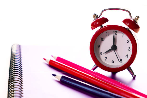 istock School time minimalistic concept. Colored pencils and notebooks and a red alarm clock.Time management. 1166245697