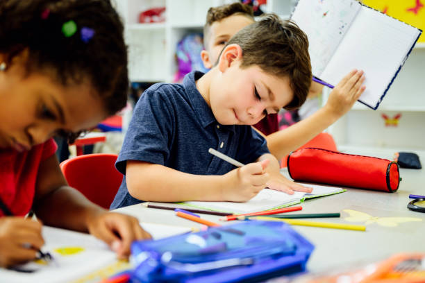 istock Focused Hispanic schoolchildren drawing with colored pencils 1166252050