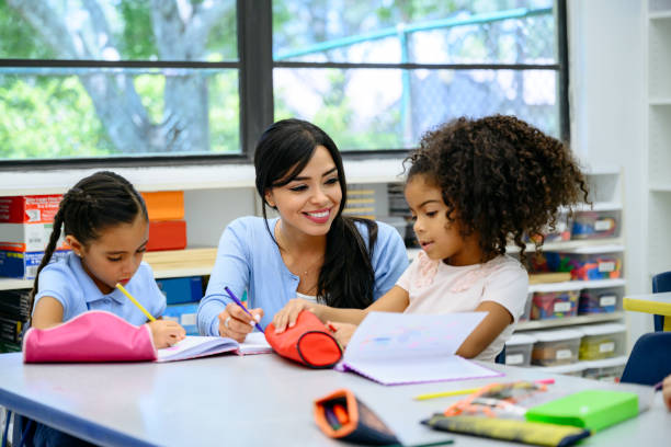 istock Hispanic schoolgirls working on drawings with teacher 1166252056