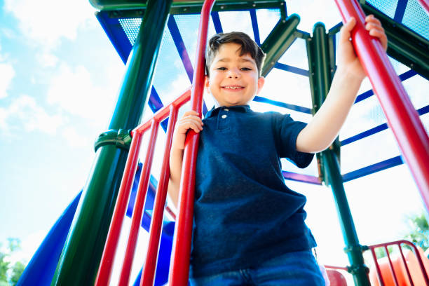 istock Happy Hispanic schoolboy climbing on playground equipment 1166252072