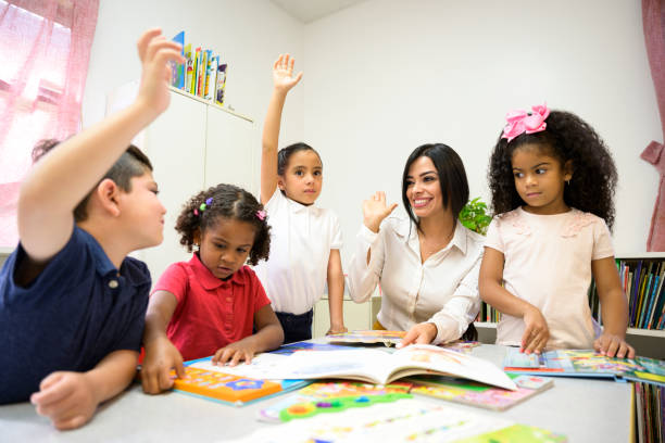 istock Hispanic schoolteacher encouraging students to raise hands 1166252078