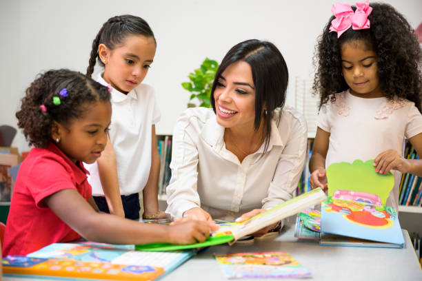 istock Hispanic students and schoolteacher looking at picture books 1166252091