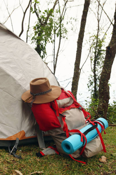 istock A backpack with a mat and a hat near to a tent on a grass in a camping on a background of forest. 1166252123