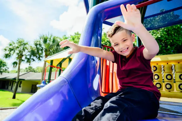 Photo of Smiling Hispanic schoolboy on outdoor playground equipment