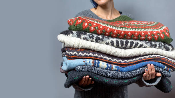 istock Young woman hold pile of sweaters 1166253194
