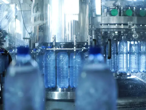Filling line of sparkling water in a pet bottle. Mini factory for bottling water.
