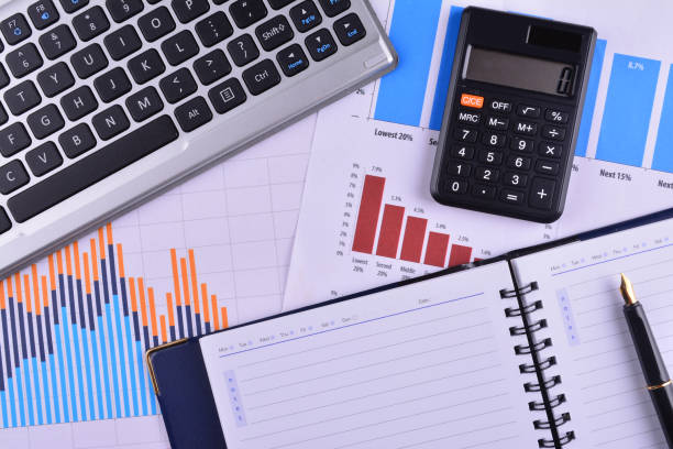 istock Blank Notebook with calculator, keyboard and fountain pen on graphs, charts and business table. The workplace of business people 1166254290