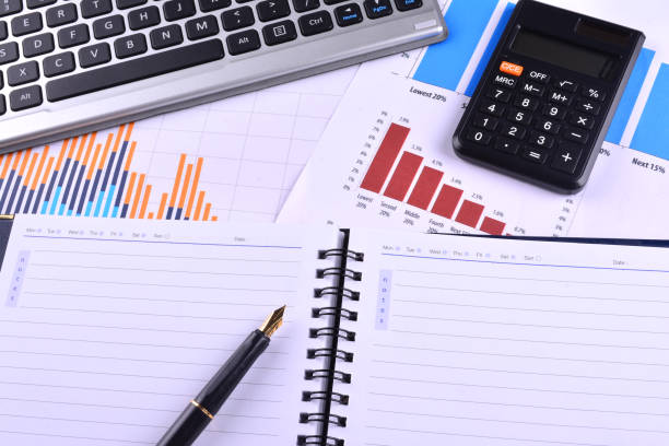istock Blank Notebook with calculator, keyboard and fountain pen on graphs, charts and business table. The workplace of business people 1166254430