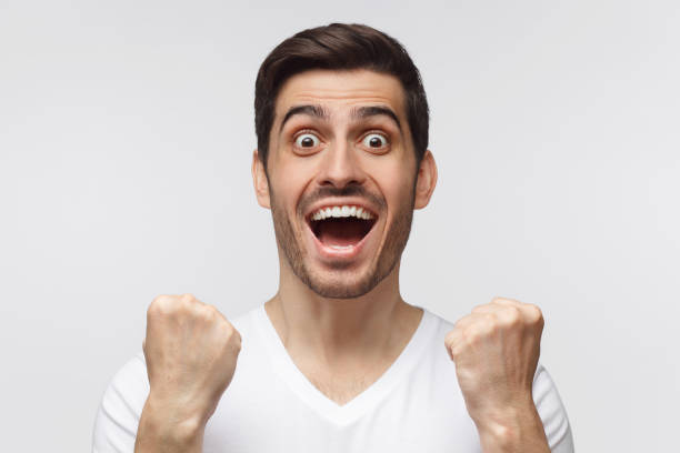 istock Young man shouting while his team win, raised both fist in victory gesture, isolated on gray background. Casual soccer fan concept 1166255899