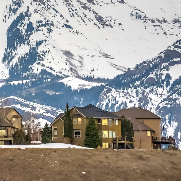 istock Square frame Neighborhood built on a hill overlooking a striking snowy mountain in winter 1166257687