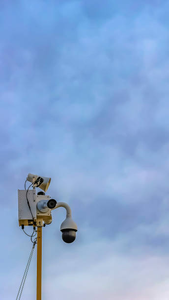 istock Vertical frame Outdoor security camera isolated against a cloudy blue sky background 1166259629