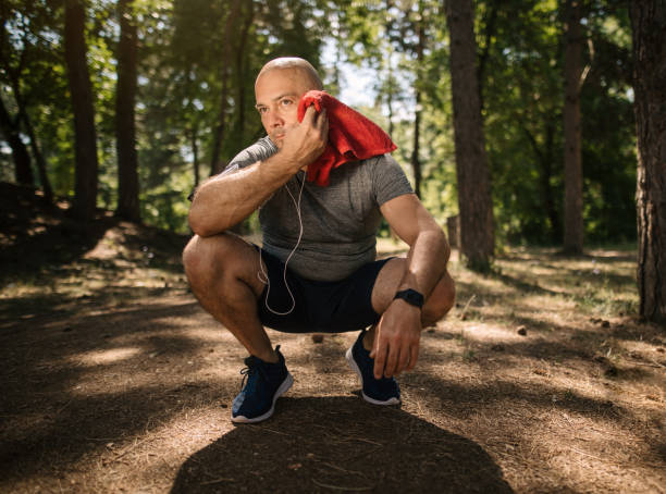 istock Senior man with a towel exercising in the forest 1166259637