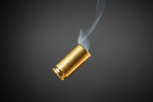 smoking bullet casing just fired out of a handgun tumbling through the air