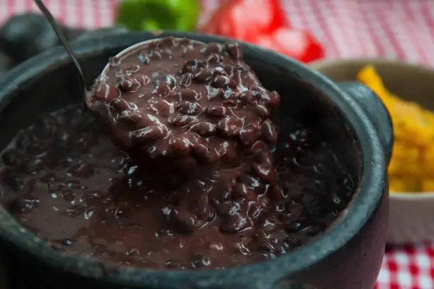 Rustic pan stuffed with fresh black beans lifted by a spoon