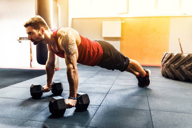 istock Muscular man doing pushup exercise with dumbbell 1166262138