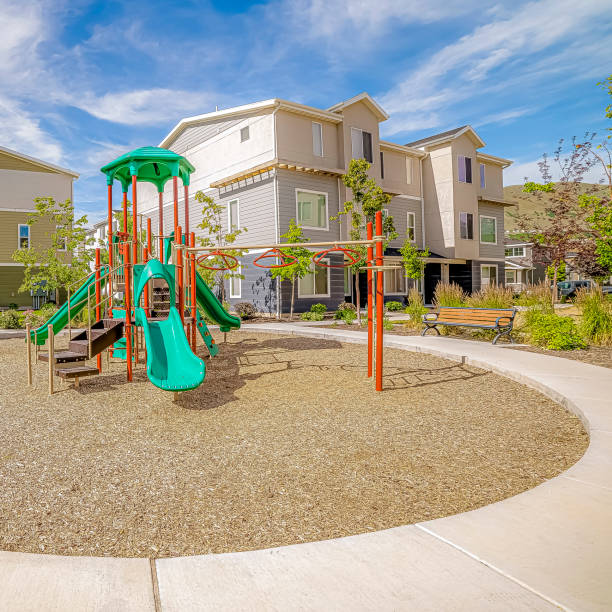 istock Square frame Playground surrounded by a circular pathway and benches under cloudy blue sky 1166262328