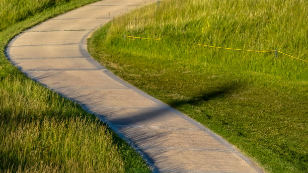istock frame Pathway that winds through a grassy terrain with houses in the background 1166262697