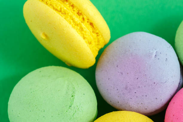 colorful macarons or macaroons cookies on green background. top view