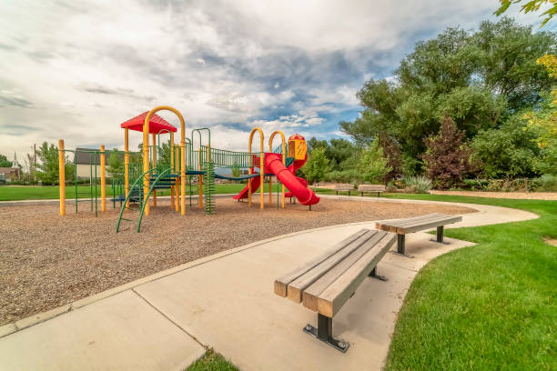 istock Playground on a relaxing park with wooden benches along the paved pathway 1166264745