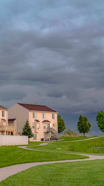 istock Vertical Home facade overlooking an expansive green field with a paved pathway and pond 1166264954