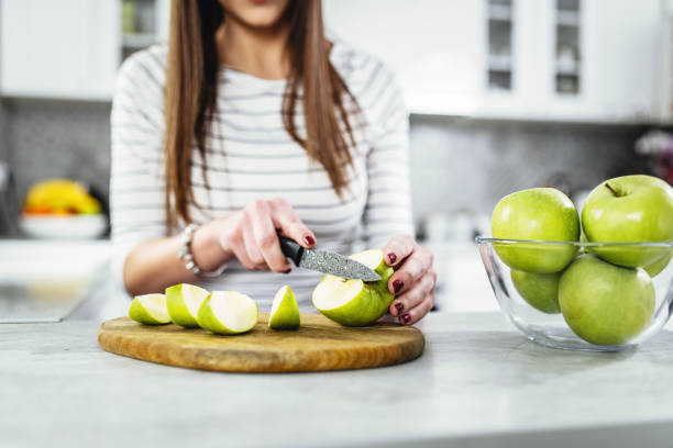 Picture of beautiful woman in the kitchen. Cutting an apple for a breakfast. stock photo