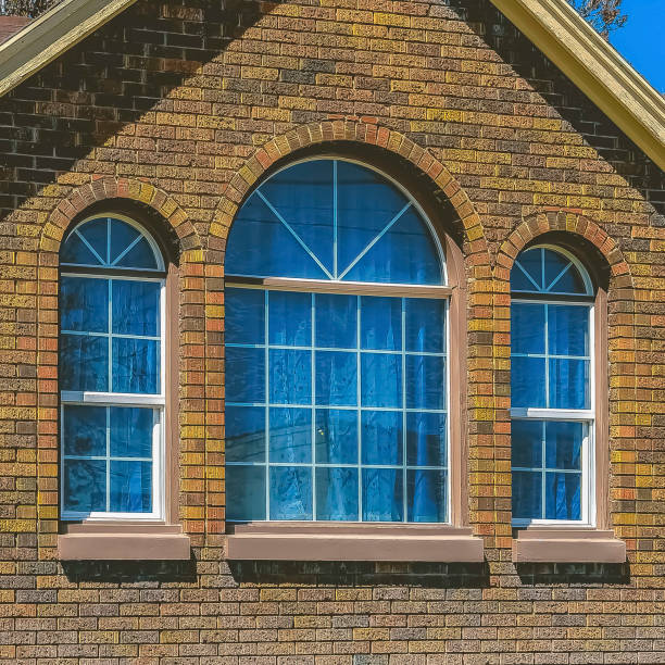istock Square frame Home with brick wall and arched windows against blue sky on a sunny day 1166266109