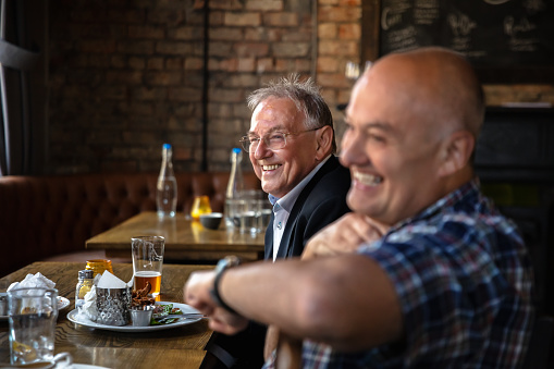 Two men in their 60s enjoying lunch in a traditional British pub.