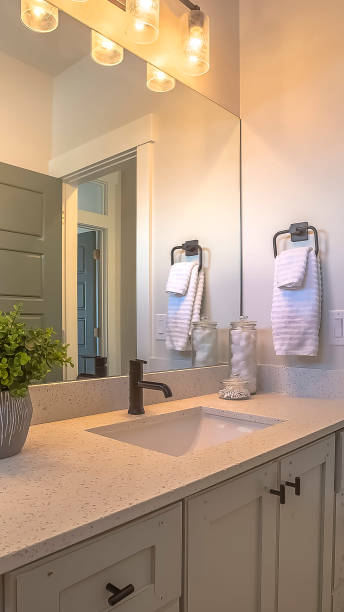 istock Vertical Mirror and vanity unit inside a bathroom with white wall and brown wood floor 1166266891