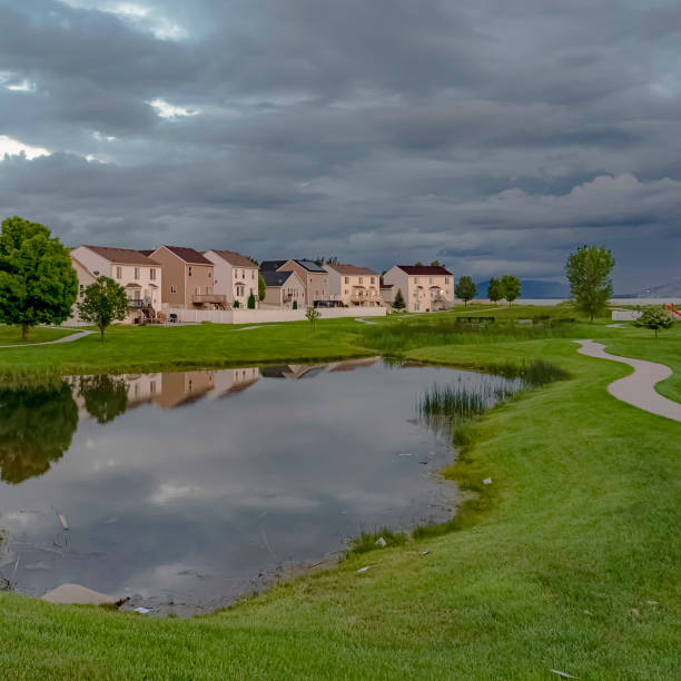 istock Square frame Scenic neighborhood park with a shiny pond and pathway under an overcast sky 1166267166