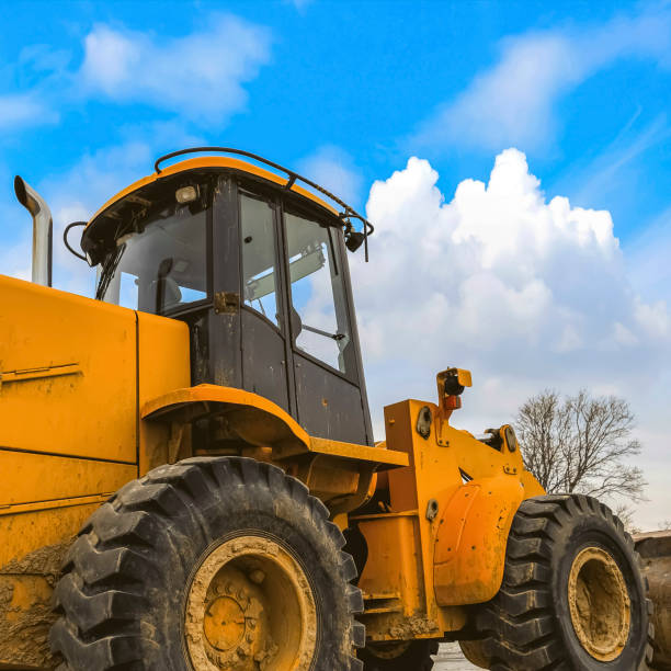 istock Close up of a dirty yellow loader with black rubber wheels and empty cab 1166267261