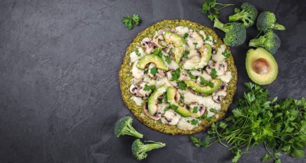 grüner brokkoli-teig krustenpizza mit avocado, käse. low carbs, ketogene diät vegane vegetarische pizza auf schiefer hintergrund top-ansicht - low back stock-fotos und bilder