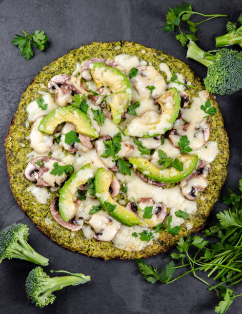 grüner brokkoli-teig krustenpizza mit avocado, käse. low carbs, ketogene diät vegane vegetarische pizza auf schiefer hintergrund top-ansicht - low back stock-fotos und bilder