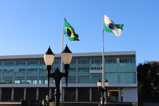 Late winter afternoon pleasant in the Civic Center, allowed the capture in this photo of the Brazilian and Paraná flags to tremble, the government building of the government of the State of Paraná, Iguaçu Palace, and the traditional luminaires of Curitiba.