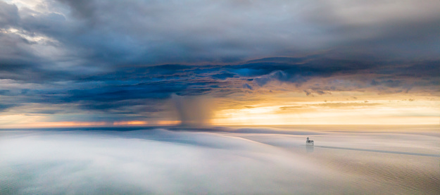Unearthly storm squall, between two layers of clouds, drone aerial with Lake Michigan rain squall above, and fog on the waters below.