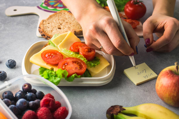 午前中に学校に健康的な昼食を与える母 - child human hand sandwich lunch box ストックフォトと画像