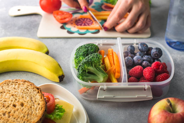 mère donnant le déjeuner sain pour l'école le matin - préparation des aliments photos et images de collection