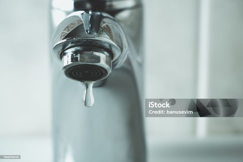 water drop dripping from the tap water drop dripping from the tap and water shortage Faucet Stock Photo