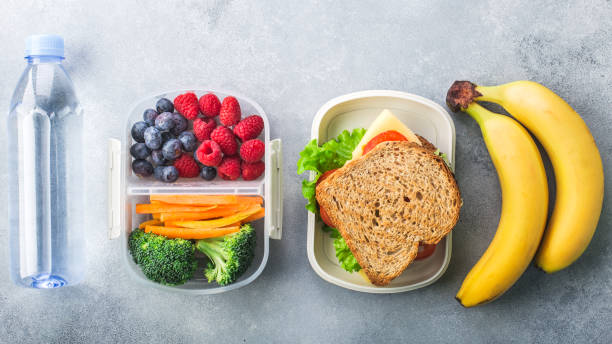 boîte à lunch d'école avec des légumes sandwich amandes d'eau et des fruits sur la table grise saine - lunch packed lunch lunch box apple photos et images de collection