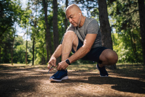 istock Jogging man tying his shoes in the forest 1166280704