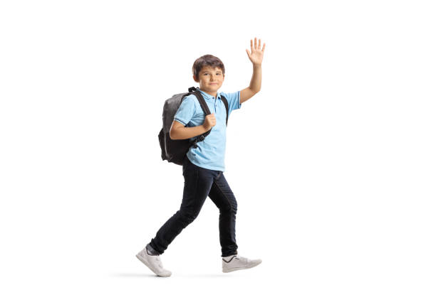 Schoolboy with a backpack running and waving at the camera Full length shot of a schoolboy with a backpack running and waving at the camera isolated on white background kid waves stock pictures, royalty-free photos & images
