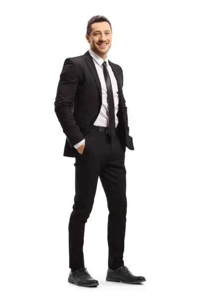 Full length shot of a young man in a black suit posing isolated on white background