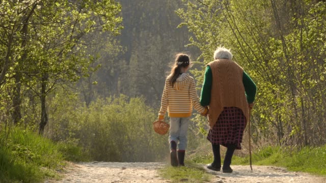 Senior Woman and Child Walking Down The Road. Holding Hands.
