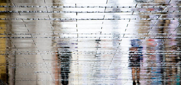 istock Blurry puddle reflection shadow silhouettes of  people walking on a rainy summer day 1166288250